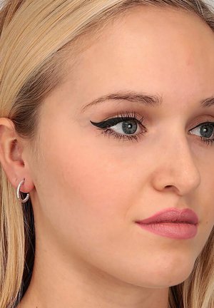 Silberne Creolen mit einem strukturierten Design. Das Model hat glattes, blondes Haar, einen geschwungenen Eyeliner und einen sanften rosa Lippenstift.