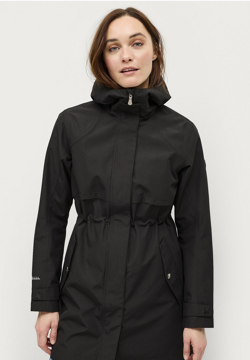 Cappotto impermeabile nero con vita cinchata, colletto alto, chiusura frontale con zip e tasche laterali. Presenta polsini regolabili e una texture liscia.