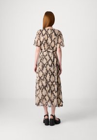 Vestido largo y fluido hecho de un tejido ligero y transparente en color beige con un patrón de tie-dye negro. Presenta mangas cortas y una cintura ceñida con cinturón.