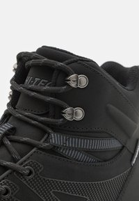 Botas de senderismo negras con parte superior de sintético texturizado, ojales de metal y cordones. Presenta franjas horizontales y acentos de goma para mayor soporte.