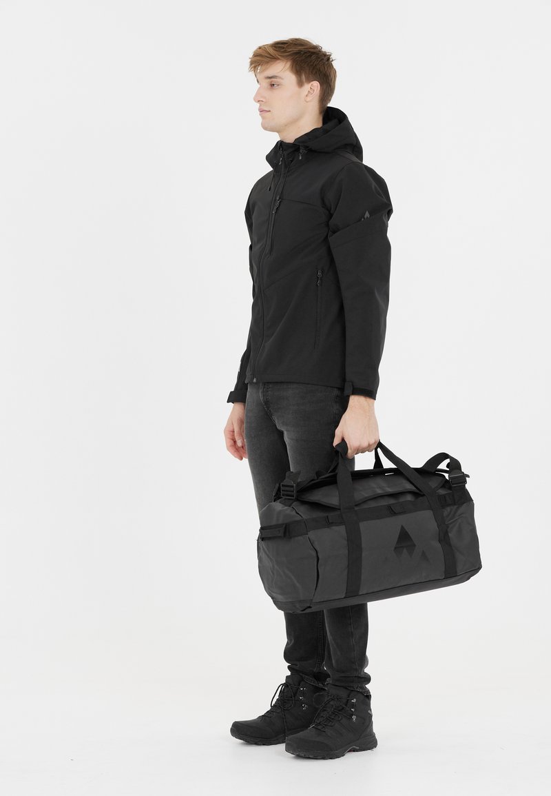 Mustaväriinen duffel-laukku, jossa on säädettävät hihnat, tyylikäs muotoilu ja kontrastinen kolmion muotoinen kuvio. Sileä pinta, valmistettu kestävästä materiaalista.