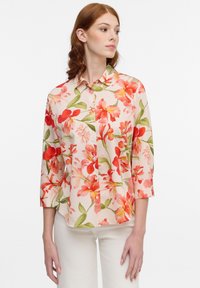 Floral blouse featuring a light background with red and green botanical patterns, button-front closure, and three-quarter sleeves.