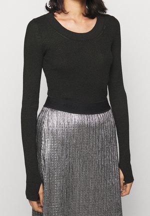 Black ribbed long-sleeve top paired with a silver pleated skirt featuring a black waistband with embossed "HUGO" logo. Textured materials.