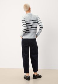 Hellgrauer gestreifter Pullover mit navyblauen horizontalen Streifen, kombiniert mit dunkelblauen Cordhosen und schwarzen Schuhen. Weiche Stoffeigenschaft.