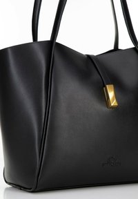 Borsa tote in pelle nera con texture liscia, una chiusura geometrica dorata e logo impresso alla base. Presenta due manici lunghi per il trasporto.