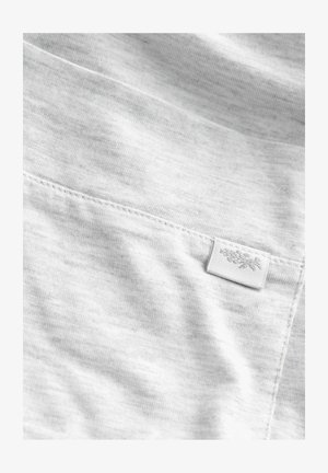 Vaaleanharmaa kangas, jossa on sileä pinta ja hienovarainen heather-kuvio. Kulmassa on ommeltu etiketti, jossa on kukkakuva.