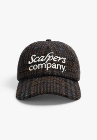 Bonnet en laine foncée avec un motif texturé, arborant un logo brodé blanc "Scalpers Company" à l'avant et une visière courbée.