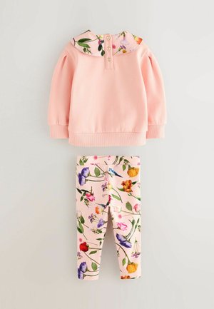 Rosa Sweatshirt mit blumenförmigem Kragen und Dreiknopfverschluss, kombiniert mit rosa Leggings, die ein blumiges Muster in verschiedenen Farben aufweisen.