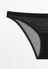 Sort bikini bund, der har et glat stof og gennemsigtige mesh-paneler, med et sømløst design og en tynd taljebånd for minimal dækning.