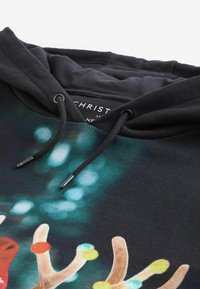 Sudadera negra con un diseño colorido de cuernos de reno con puntos. El material es de tejido suave; incluye cordones ajustables y etiqueta.