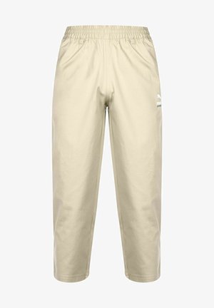 Beige joggebukser med elastisk liv. Laget av mykt materiale, med en hvit logo på venstre bein og en avslappet, cropped passform.