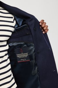 Abrigo de marina con un forro de satén suave, dos botones y un bolsillo interior con cremallera. Etiqueta visible con logo de ancla y nombre de la marca: Armor Lux.