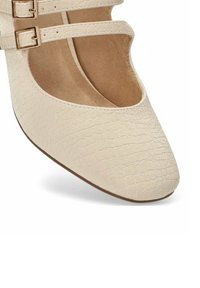 Zapatos Mary Jane color crema con una parte superior de cuero texturizado con patrón de cocodrilo, que presentan dos correas con hebillas doradas y una punta redondeada.