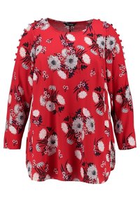 Rød blomsterbluse med lange ærmer, der har en rund halsudskæring, sort-hvide blomster mønstre og dekorative knapdetaljer på skuldrene.