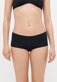 Sorte svømmebukser med en glat tekstur, lav skjæring og minimalistisk design. Har en bred talje for komfort og dækning.