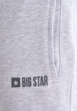 Helehall kangas vertikaalse luku taskuga ja musta värvi "BIG STAR" logo tähe sümboli kõrval alumisel vasakul küljel.