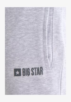 Helehall kangas vertikaalse luku taskuga ja musta värvi "BIG STAR" logo tähe sümboli kõrval alumisel vasakul küljel.