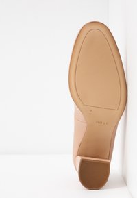 Chaussure en cuir beige avec un bout arrondi, texture lisse et semelle en caoutchouc avec un motif nervuré ; hauteur du talon modérée.