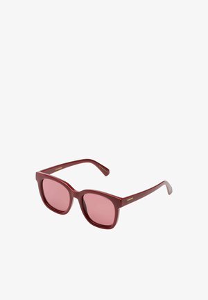 Lunettes de soleil en plastique rouge avec de grandes montures carrées et des verres roses. Présente un logo doré sur la branche. Texture lisse et design aux couleurs vives.