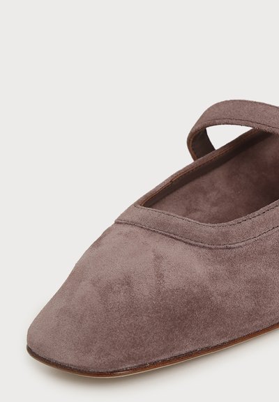 Gros plan d'une chaussure Mary Jane en daim mauve avec une seule bride et un bout carré, présentée sur fond blanc.