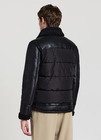 Veste noire matelassée avec manches en cuir et col texturé doublé en polaire. Présente des sections matelassées et un design élégant.