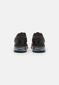 Zapatillas deportivas negras con parte superior de malla transpirable, detalles en naranja y suela translúcida con amortiguación de aire. Presentan un destacado logo "AIR MAX".