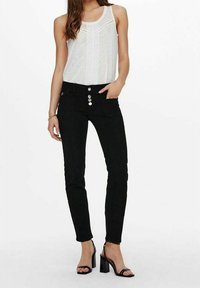 Svarta denim skinny jeans med hög midja, fem fickor och knäppning med knapp. Matchas med en vit linne och svarta klacksandaler.