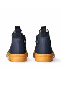 Stivaletti alla caviglia blu navy con tomaia sintetica liscia, suola in gomma marrone chiaro e fibbia laterale regolabile. Presentano un inserto posteriore testurizzato per facilitare la calzata.