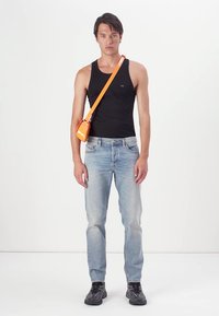 Čierne tielko, modré džínsy a čierne tenisky; oranžová crossbody taška; minimalistický dizajn bez viditeľných vzorov alebo log.