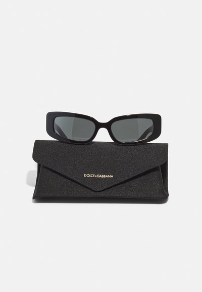 Black rectangular sunglasses with dark lenses, placed on a textured black case featuring a golden "DOLCE&GABBANA" logo.