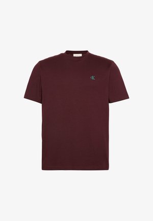 Prosty bordowy t-shirt z krótkim rękawem i okrągłym dekoltem, z małym jasnoniebieskim logo „cK” na lewej piersi.