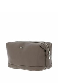 Trousse de toilette en cuir marron avec surface texturée, fermeture éclair argentée, et logo "BOSS" embossé sur un côté. Forme compacte et rectangulaire.