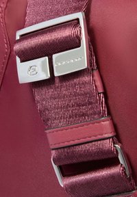 Primer plano de una correa de tela marrón brillante con una hebilla de metal plateado grabada con el logo "PIQUADRO".