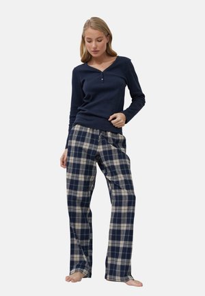 Granatowa koszulka henley z długim rękawem i listwą z guzikiem, w połączeniu z spodniami flanelowymi w kratę w odcieniach granatu i kremu, o luźnym kroju i prostych nogawkach.