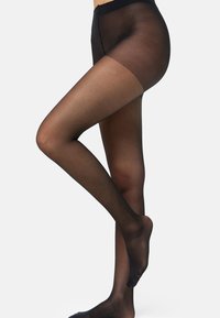 Medias negras transparentes que presentan una textura suave, una pretina alta y un acabado translúcido, proporcionando cobertura desde la cintura hasta los dedos de los pies.