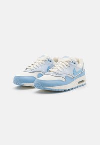 Svijetloplave tenisice s gornjim dijelom od mrežice i kože, gumeni potplat i podstavljeni ovratnik. Imaju Nike logo i đon s vezicama.