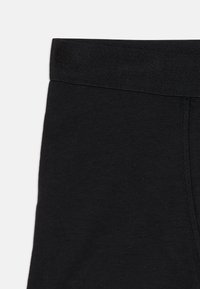 Schwarze Leggings mit einem weichen, dehnbaren Bund und glatter Stoffstruktur. Das Design betont eine figurschmeichelnde Silhouette ohne Muster.