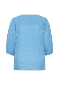 Blouse bleu clair présentant un motif texturé à losanges, manches trois-quarts bouffantes et un col rond.