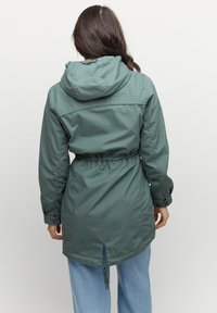 Zielona wodoodporna parka z ściągaczem w talii, kapturem i zapięciem na guziki; posiada wentylację z tyłu. Gładki, lekki materiał.