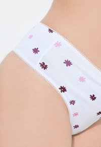 Culotte en coton blanc avec de petits motifs floraux en rose foncé et clair. Une délicate dentelle borde la taille pour un effet raffiné.