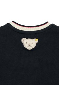 Marineblauwe crewneck sweatshirt met een beige berenkop borduursel op de achterkant, met een geribbelde kraag die is geaccentueerd in wit en rood.
