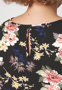 Floral-patterned fabric in black, featuring pink, yellow, and blue flowers. Keyhole opening at the back with a black button detail.