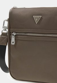 Brown synthetic bag featuring a textured surface, silver hardware accents, a triangular logo, and a zippered pocket. Adjustable strap included.