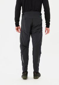 Heren buitenbroek in donkergrijs met een slim fit, ritszakken aan de zijkanten en reflecterende accenten, gemaakt van lichtgewicht, duurzame stof.