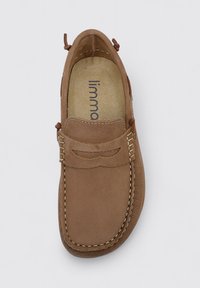 Zapato mocasín de cuero marrón con una superficie texturizada, costuras decorativas y un pequeño detalle recortado en la parte delantera. El interior tiene una plantilla con la marca.