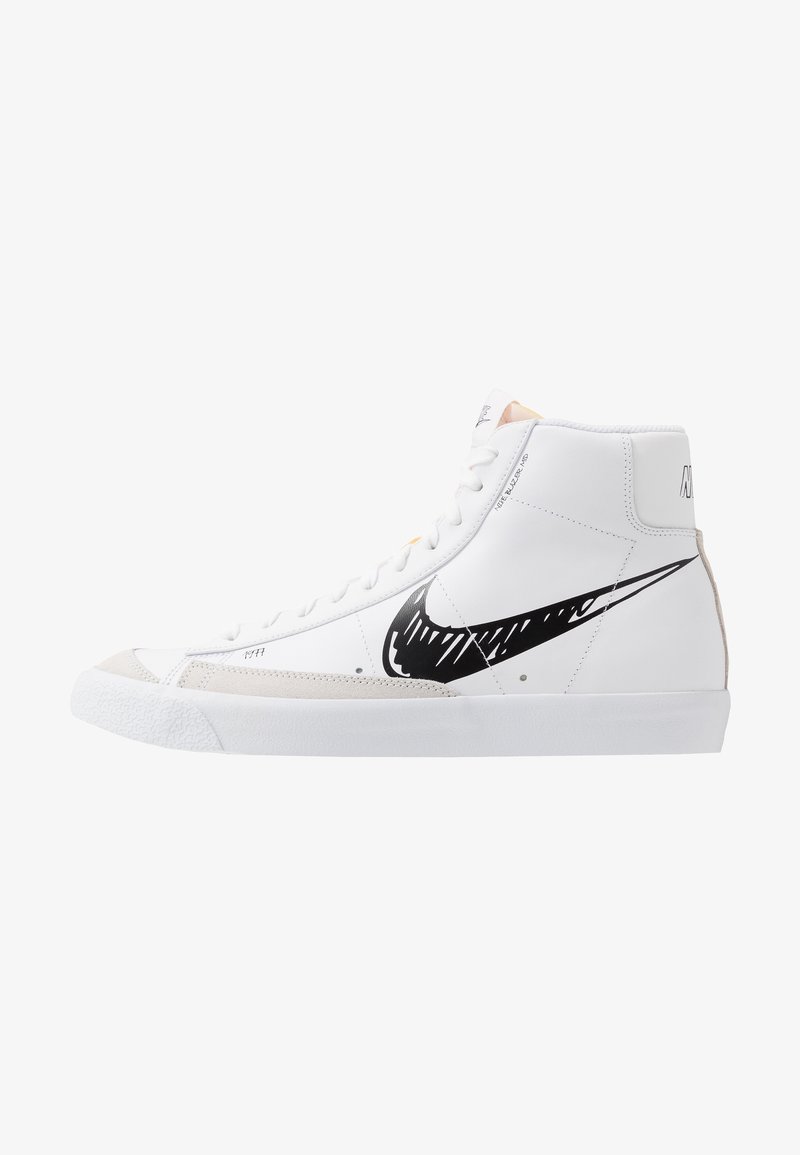 Baskets montantes blanches avec un swoosh Nike en style esquisse noir, un bout en daim beige et une semelle en caoutchouc blanche, vues de côté.