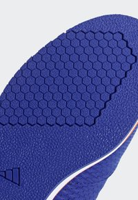 Fioletowa podeszwa sportowego buta z sześciokątnym wzorem bieżnika, teksturowaną powierzchnią i białymi detalami na krawędzi. Zaprojektowana z myślą o przyczepności i trwałości.