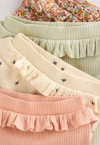 Vier Paar gerippte Shorts in Pastellfarben: Pink, Blassgrün, Creme mit Blumenmustern und Hellgelb mit kleinen Akzenten. Jede mit Rüschendetails.