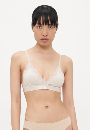 Beige bralette met een met kant afgewerkte V-hals, dunne bandjes en een gladde stof. Eenvoudig ontwerp met een zachte textuur en minimale hardware.
