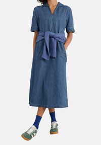 Farkkutunika lyhyillä hihoilla, V-pääntiellä ja vyötärölle solmittavalla vyöllä. Yhdistetty vihreisiin tennareihin, valkoisiin nauhoihin ja sinisiin nilkkasukkiin.